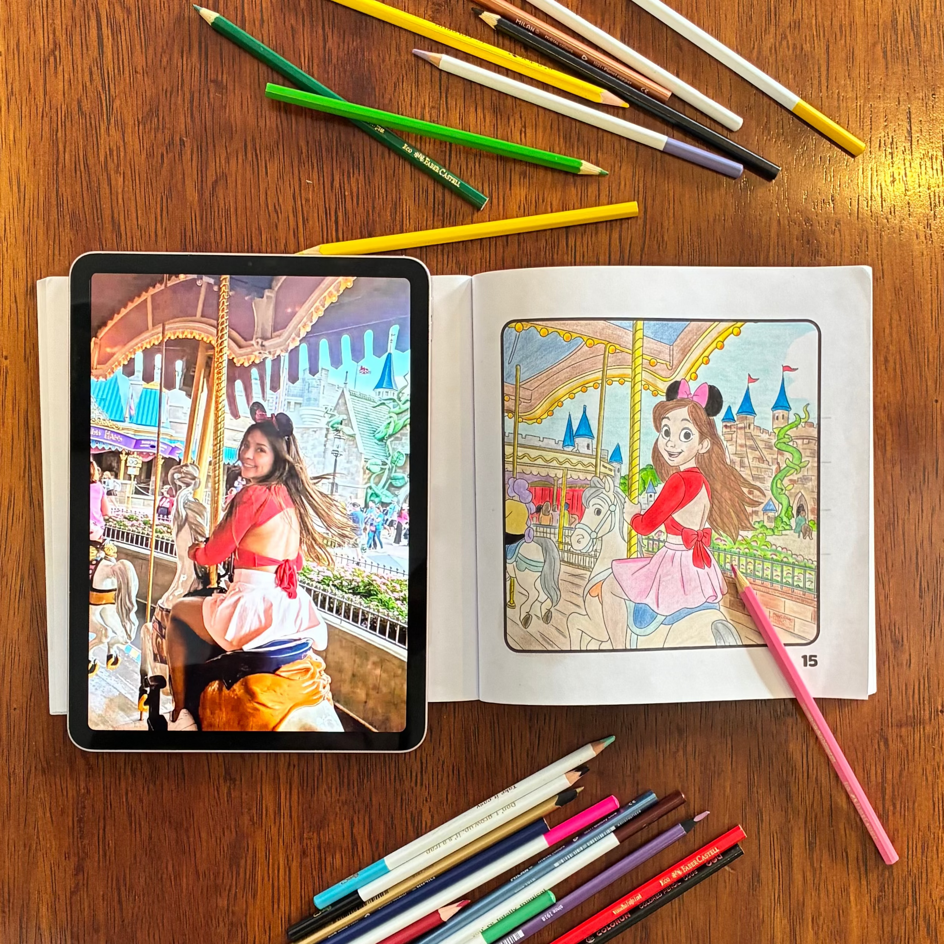 Coloring book with digital reference on a tablet, surrounded by colored pencils on a wooden table.
